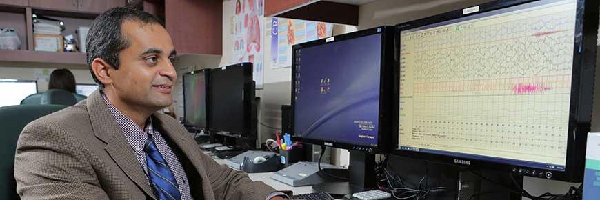 A man in a suit looking at a computer monitor with data.