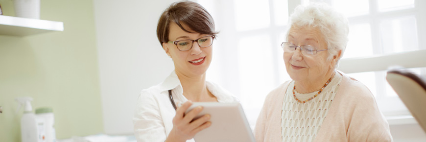 A doctor and her elderly patient look over the patient’s results on an iPad.